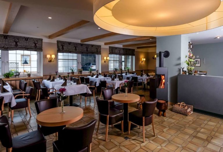Gastraum des Restaurants im Harzer Hof Scharzfeld mit eingedeckten Tischen und Holzbalkendecke