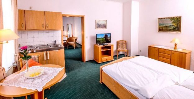 Apartment mit Küchenzeile, Doppelbett und Sitzecke am Fenster
