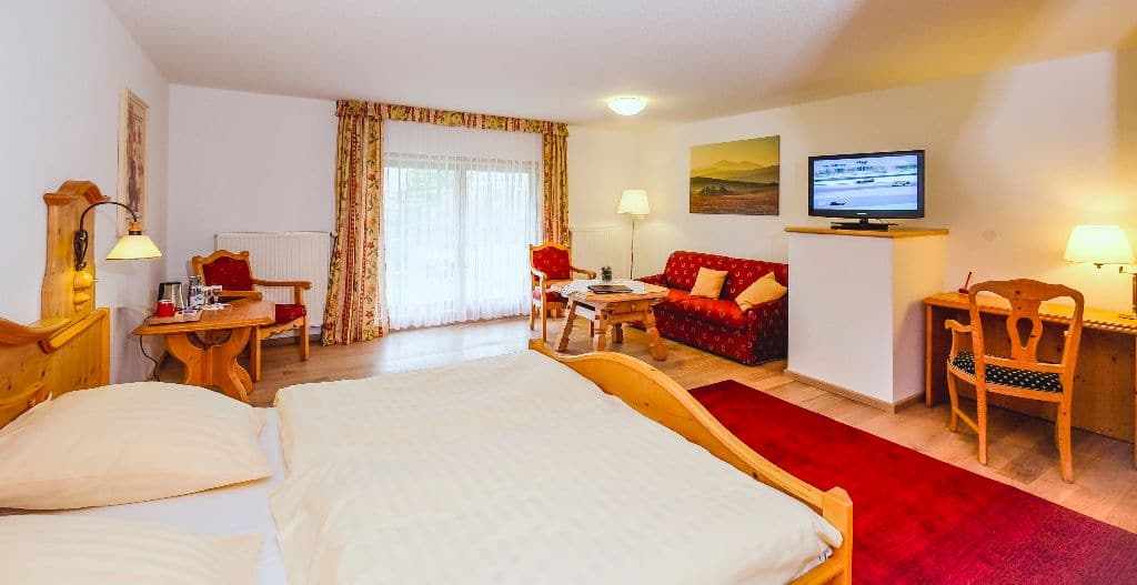 Familienzimmer mit Doppelbett, roter Schlafcouch und Fernseher
