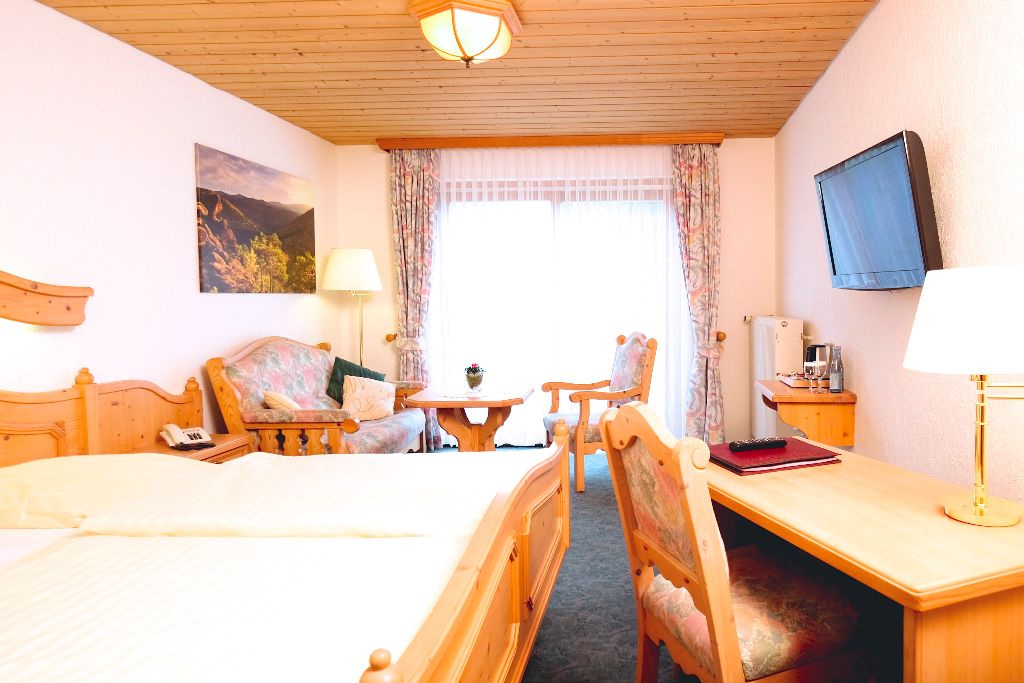 Doppelzimmer mit Holzmöbeln, Schreibtisch und Fernseher