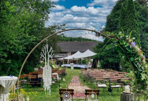 Freie Trauung im Garten mit blumengeschmücktem Bogen und Stuhlreihen