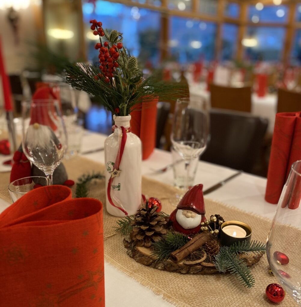 Weihnachtlich gedeckter Tisch mit roten Servietten, Kerzen und Tannengrün