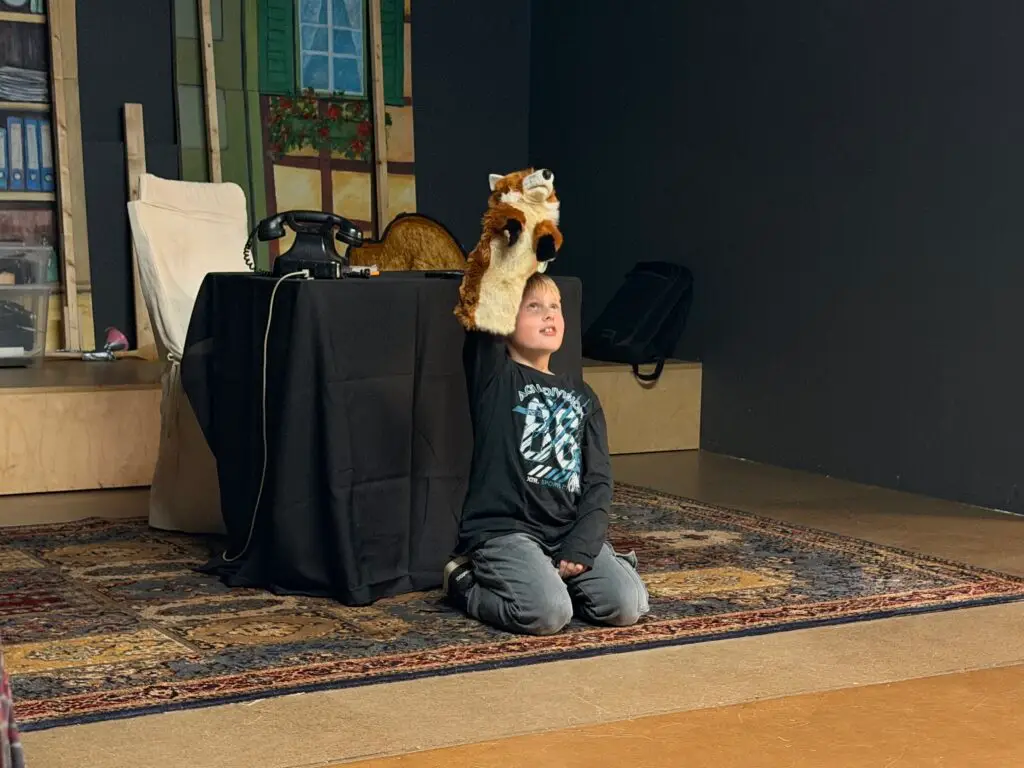 Junge spielt den listigen Freddie Fuchs mit einer Fuchs-Handpuppe auf der Bühne im Hoftheater Scharzfeld